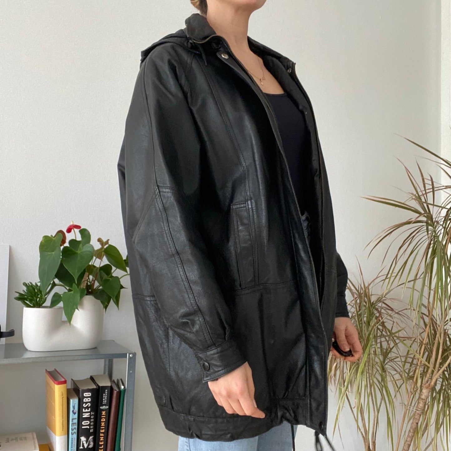 black leather jacket featuring a hood and zippered front closure.