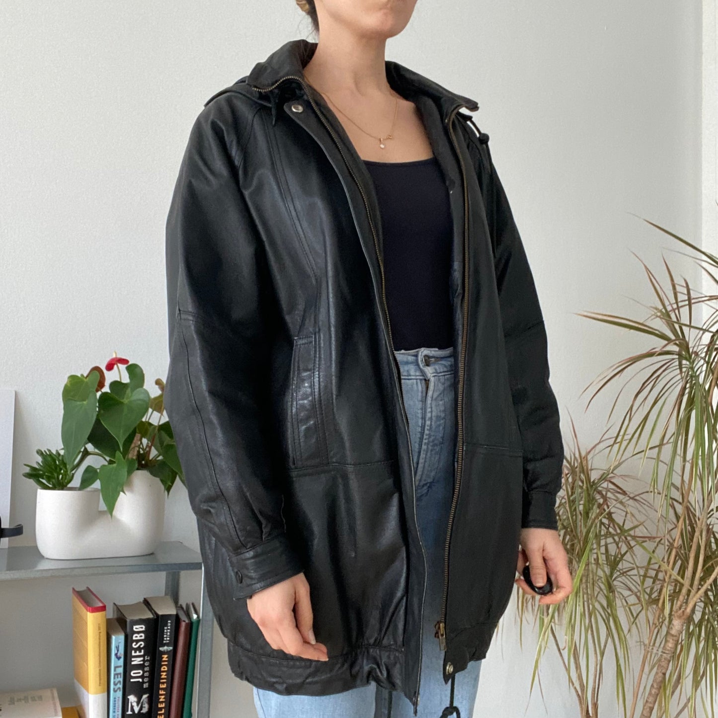 black leather jacket featuring a hood and zippered front closure.