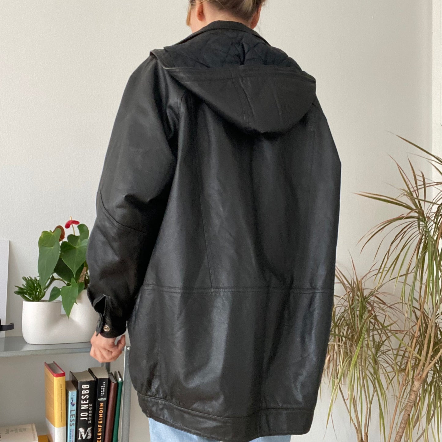 black leather jacket featuring a hood and zippered front closure.