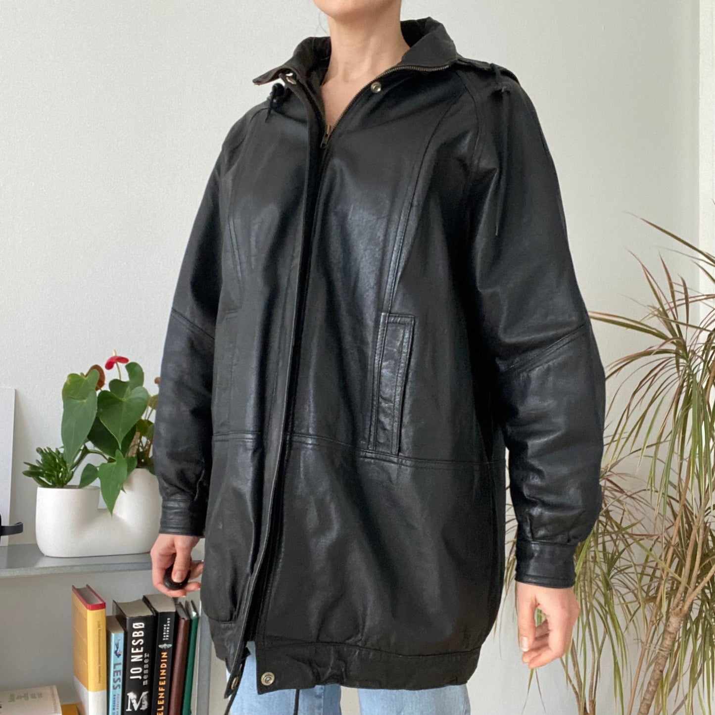 black leather jacket featuring a hood and zippered front closure.