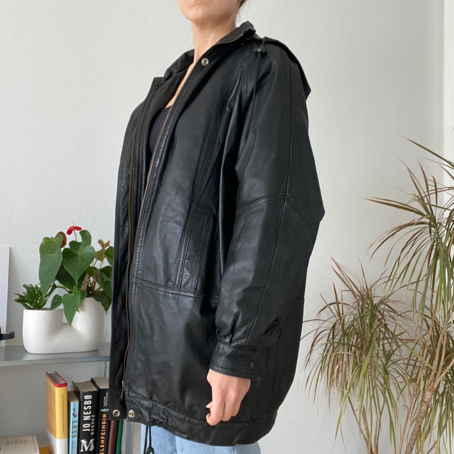 black leather jacket featuring a hood and zippered front closure.