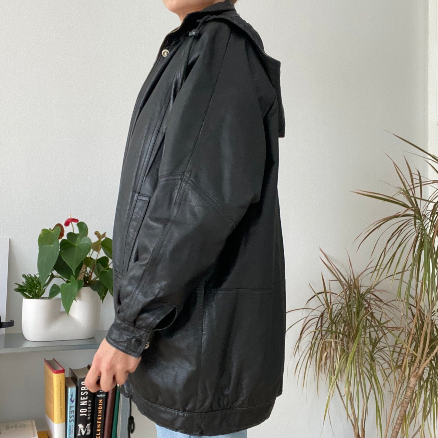 black leather jacket featuring a hood and zippered front closure.