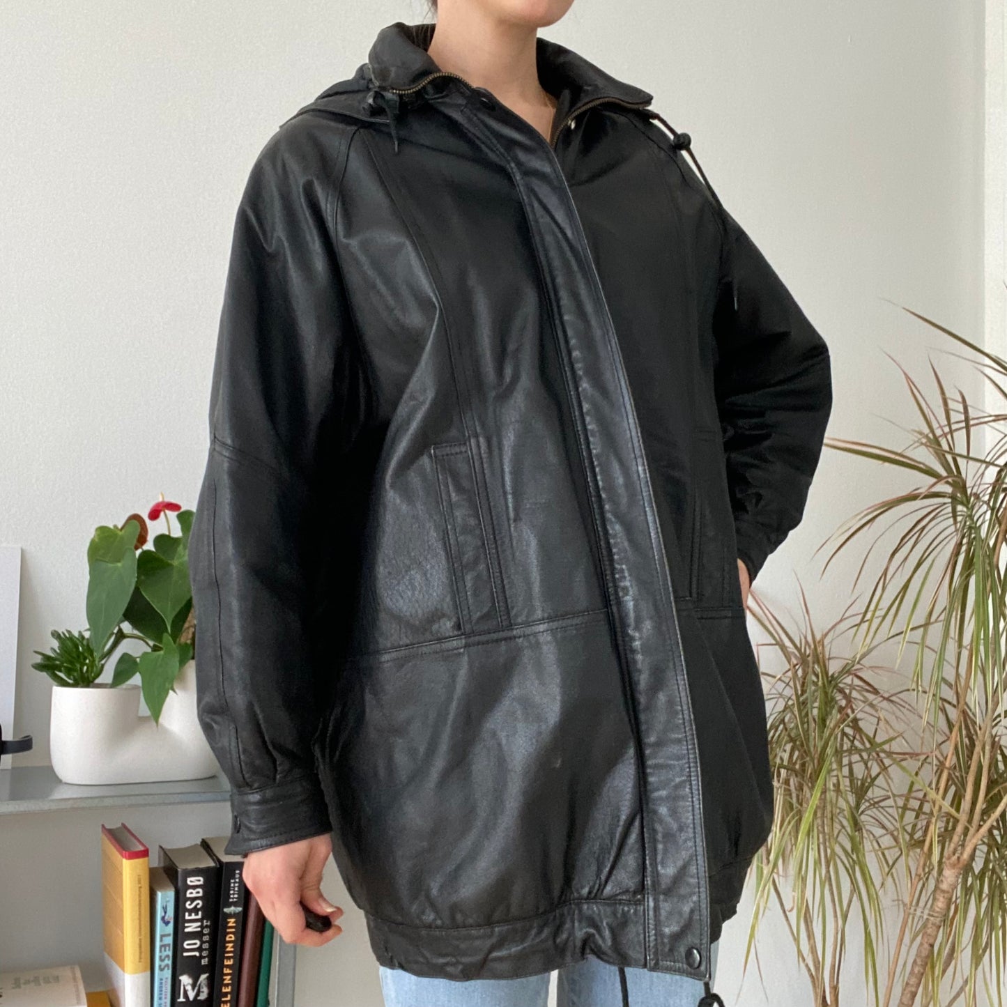 black leather jacket featuring a hood and zippered front closure.